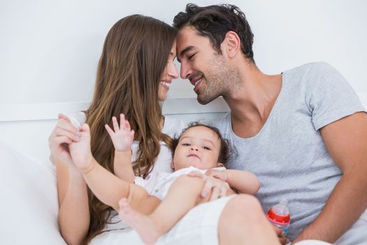 Couple enjoying with baby on bed at home 