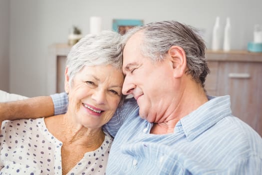 Close-up of romantic senior couple sitting on sofa at home