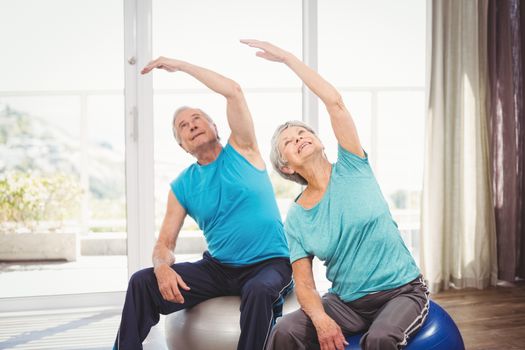Senior couple with arms raised while performing exercise at home