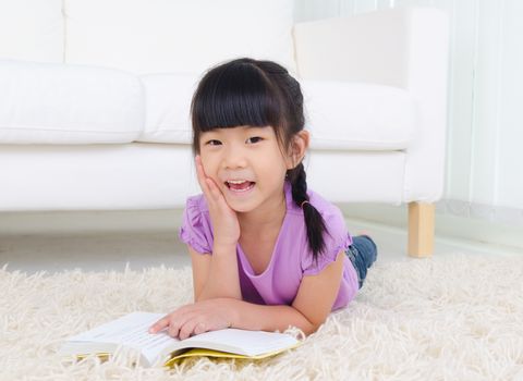Asian girl lying on the floor and reading
