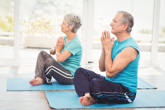 Senior couple performing yoga while sitting at home