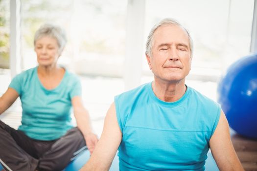 Senior couple meditating with eyes closed at home