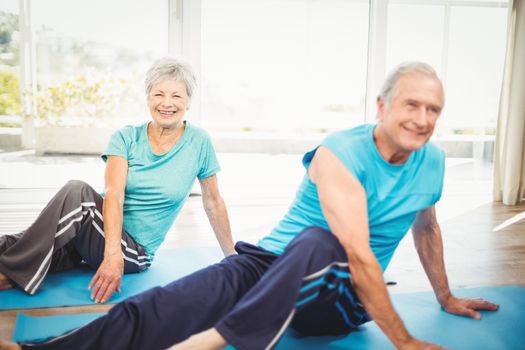 Happy senior couple doing yoga on exercise mat at home