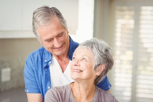 Happy romantic senior couple looking at each other in home