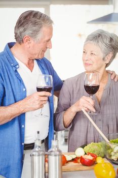 Romantic senior couple with wine glasses while standing in kitchen