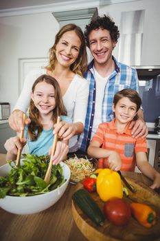 Portrait of happy parents standing with children in kitchen at home