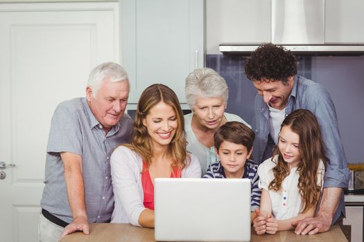 Family looking into laptop on table in kitchen at home