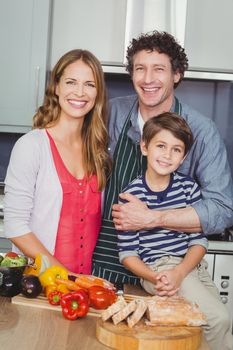 Portrait of smiling parents with son in kitchen at home
