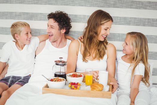 Smiling happy family enjoying breakfast on bed at home