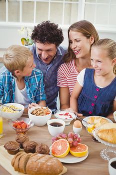 Family smiling while having breakfast at table in house