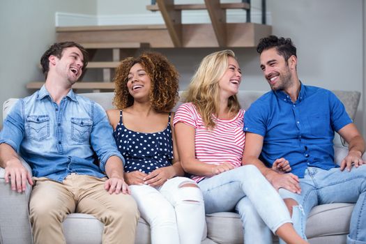 Cheerful young friends sitting on sofa at home