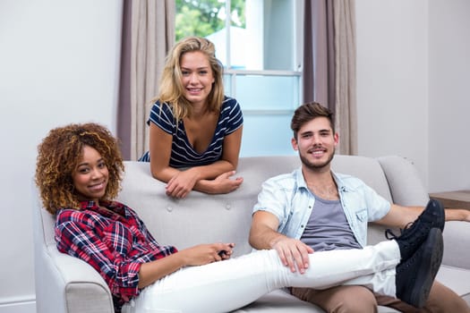 Portrait of happy multi-ethnic friends relaxing at sofa in living room