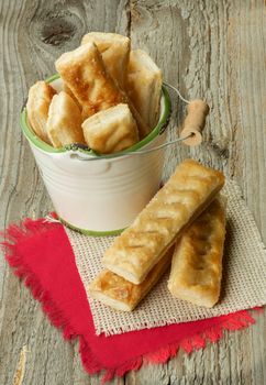 Puff Pastry Sticks Sprinkled with Sugar Crystals in White Bucket and Napkins closeup on Wooden background