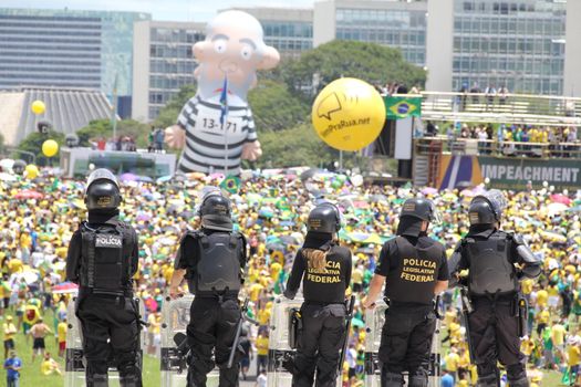 BRAZIL, Brasilia: Riot police officers stand in guard as thousands of anti-government protestors gather on the Praça dos Três Poderes (Three Powers Square), in Brasilia, during a demonstration calling for the removal of President Dilma Rousseff on March 13, 2016 . Demonstrations across the country today called for President Rousseff's exit amidst a massive corruption scandal and a deep economic recession. More than a million Brazilians have joined anti-government rallies across the country, ramping up the pressure on embattled president.