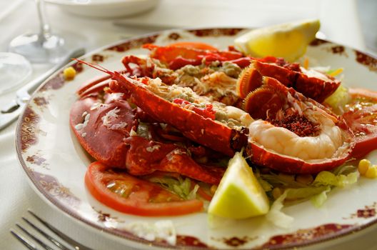 Gourmet Grilled Lobster with Vegetables Serving on Restaurant Table with Silver Fork closeup. Focus on Lobster Meat