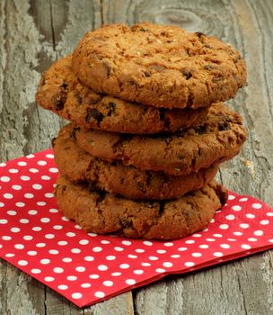 Stack of Chocolate Chip Cookies with Pieces of Nuts on Red Polka Dot Napkin closeup on Wooden background