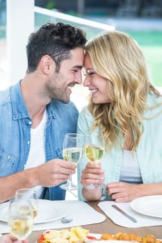 Romantic couple holding white wine glasses at home