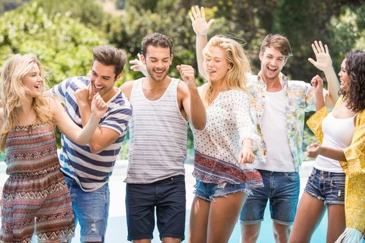 Group of happy friends dancing near pool on sunny day