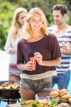 Beautiful woman having juice at outdoors barbecue party near pool