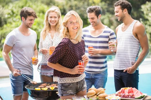 Group of friends having juice and preparing for outdoors barbecue party near pool