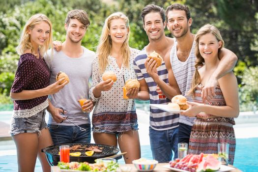 Group of friends having hamburgers and juice at outdoors barbecue party