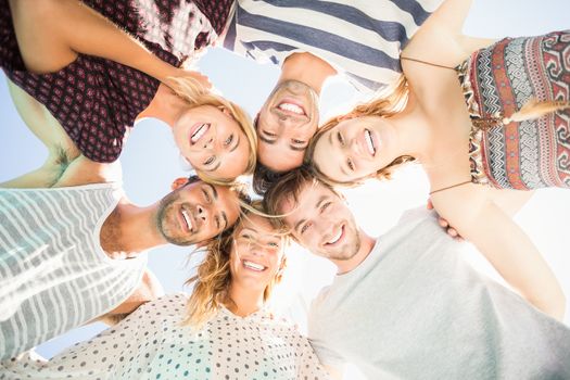 Group of happy friends forming a huddle against sky