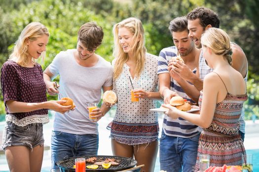 Group of friends having hamburgers and juice at outdoors barbecue party