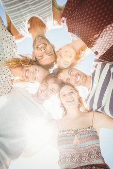 Group of happy friends forming a huddle against sky