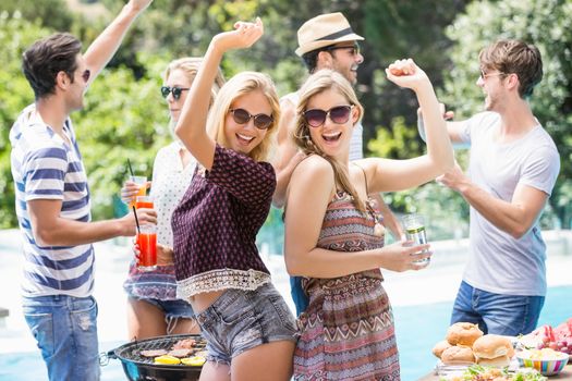 Group of friends dancing at outdoors barbecue party near pool