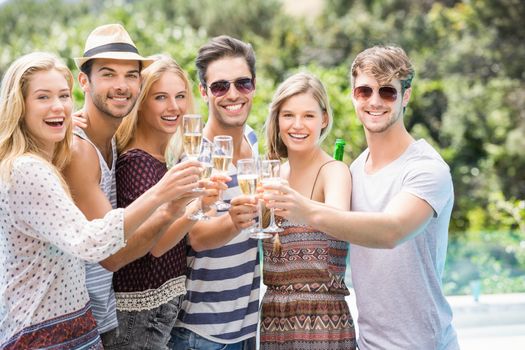 Group of happy friends toasting champagne glasses outdoors