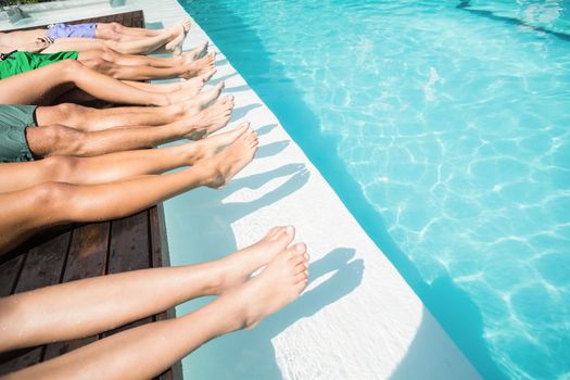 Feet of friends relaxing side by side near pool