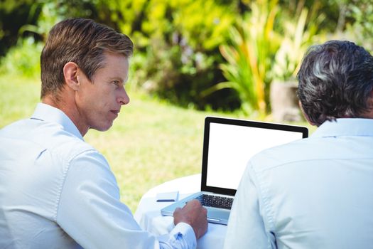 Two businessmen meeting in a restaurant using laptop in the garden