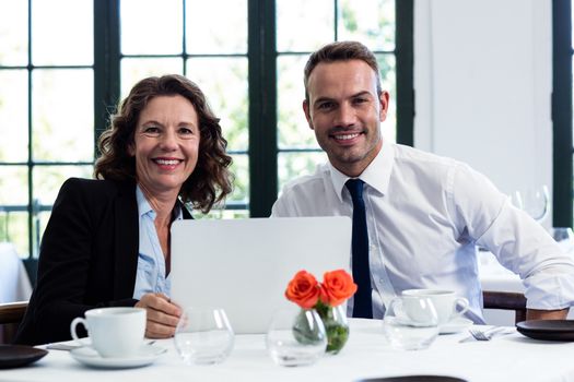 Portrait of business colleagues using a laptop while having a meeting at restaurant