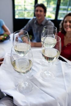 Waiter serving wine to groups friends sitting on table in restaurant