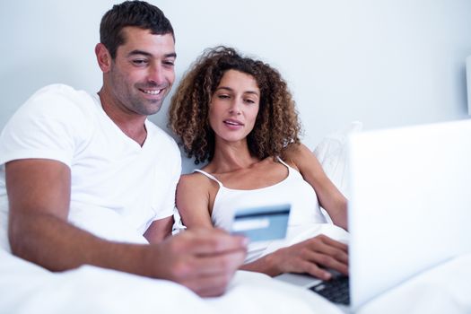 Couple shopping online in bedroom