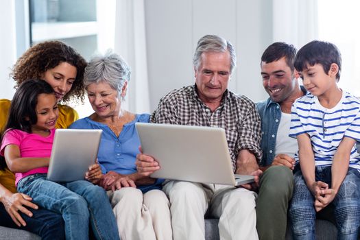 Happy family using laptop and digital tablet in living room at home