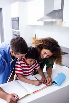 Parents helping son with homework in kitchen