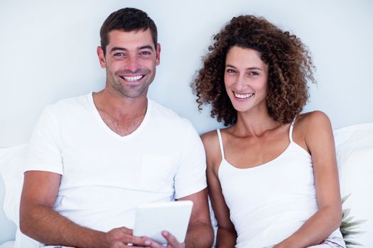 Portrait of happy couple using digital tablet on bed in bedroom