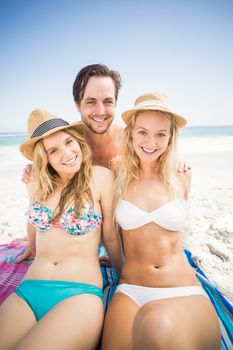 Portrait of young friends sitting together on the beach