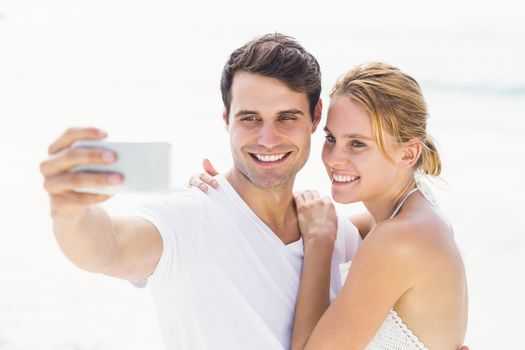 Young couple on the beach taking a selfie on mobile phone at beach