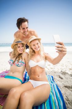 Young friends on the beach taking a selfie on mobile phone at beach