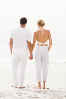 Rear view of couple standing on the beach on a sunny day