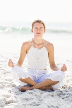 Beautiful woman in lotus position on the beach