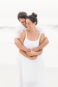 Happy couple embracing on the beach on a sunny day