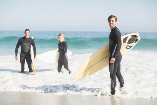 Portrait of surfer friends with surfboard standing on the beach on a sunny day