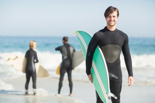 Portrait of happy man holding a surfboard on the beach on a sunny day