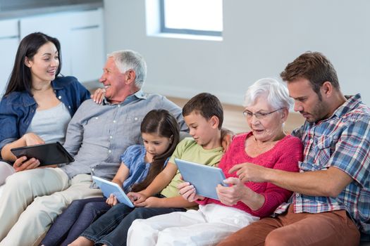 Happy family sitting on sofa using a digital tablet in living room