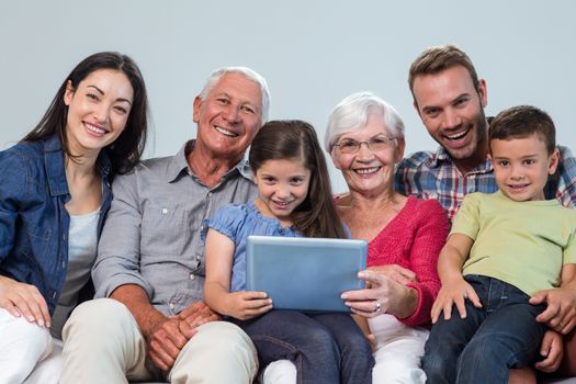 Portrait of happy family sitting on sofa using a digital tablet in living room