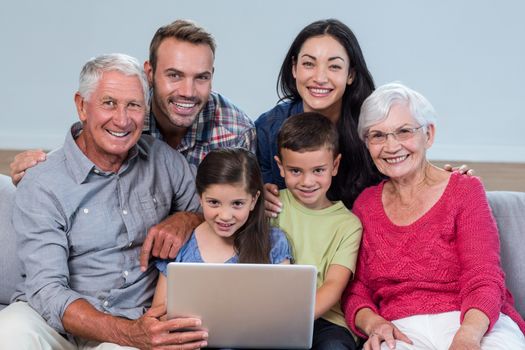 Portrait of happy family sitting on sofa using a laptop in living room