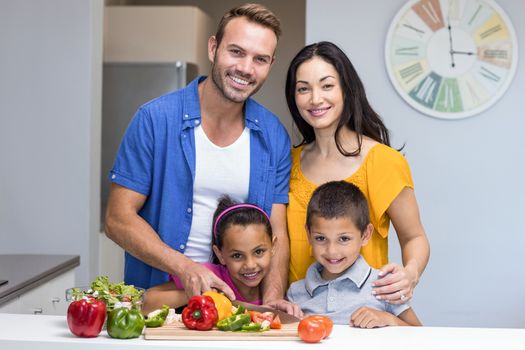 Happy family in the kitchen chopping vegetables at home